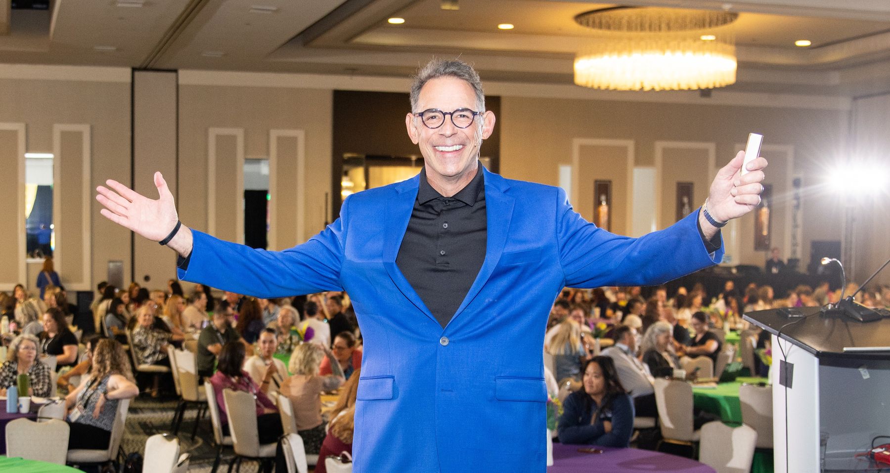 David Suson on stage before a full ballroom audience